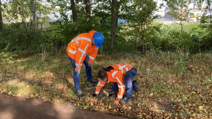 Twee personen bij een glasvezelkabel op een groenstrook
