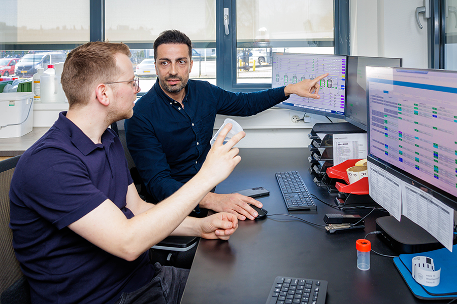 Twee mannen kijken samen naar informatie op computerschermen