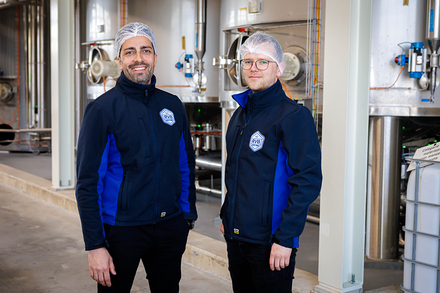 Twee mannen in blauwe jassen staan in productiehal