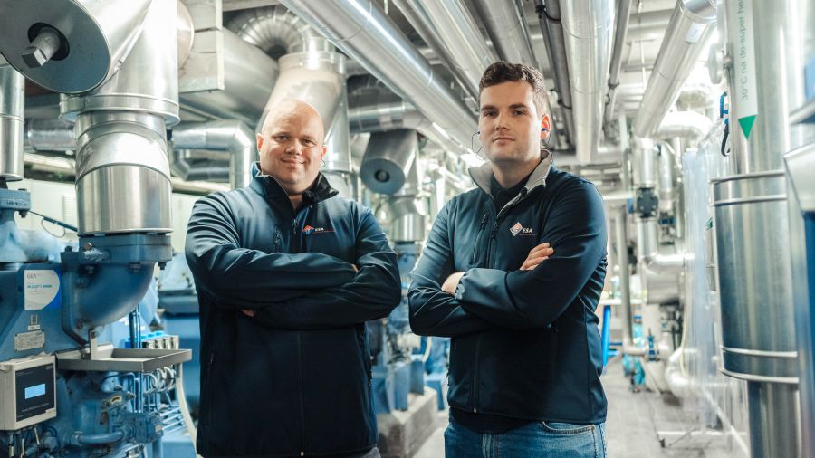 Twee medewerkers van ESA staan in een grote fabriekshal.