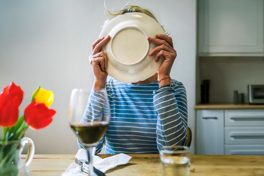 Vrouw likt haar bord af aan de eettafel.