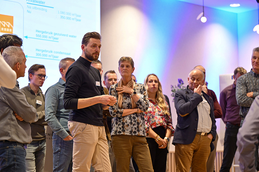 Groep mensen op podium, met elkaar aan het werk.