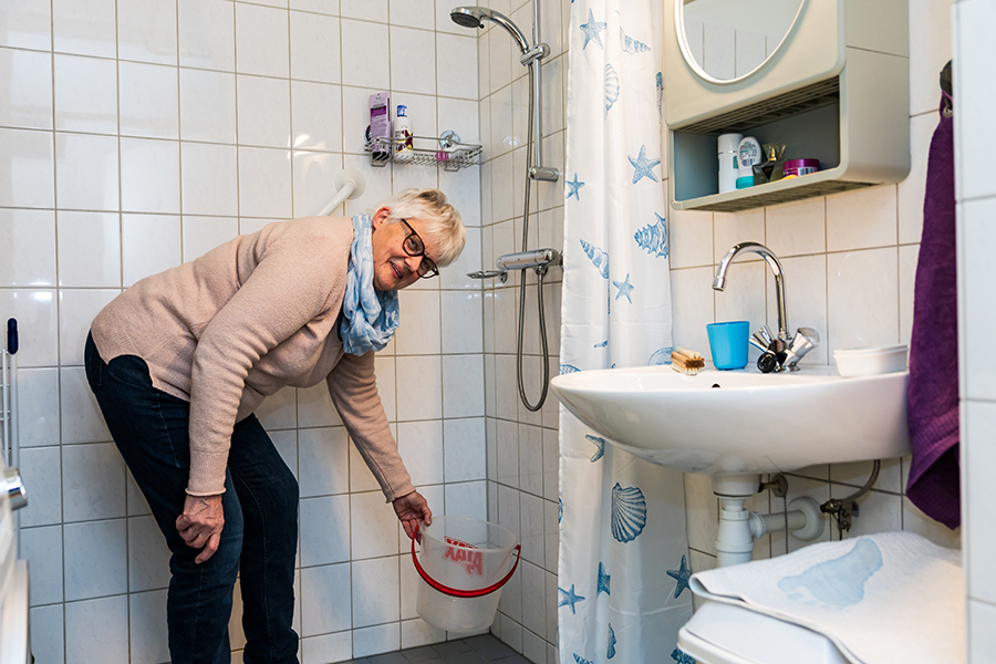 Vrouw zet emmer onder douche.