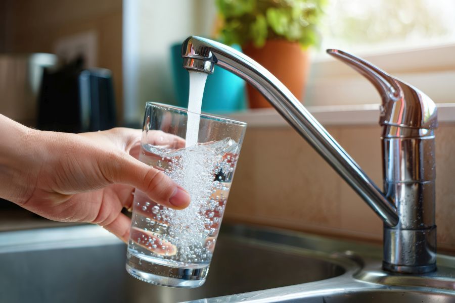 Hand vult een glas water bij de kraan