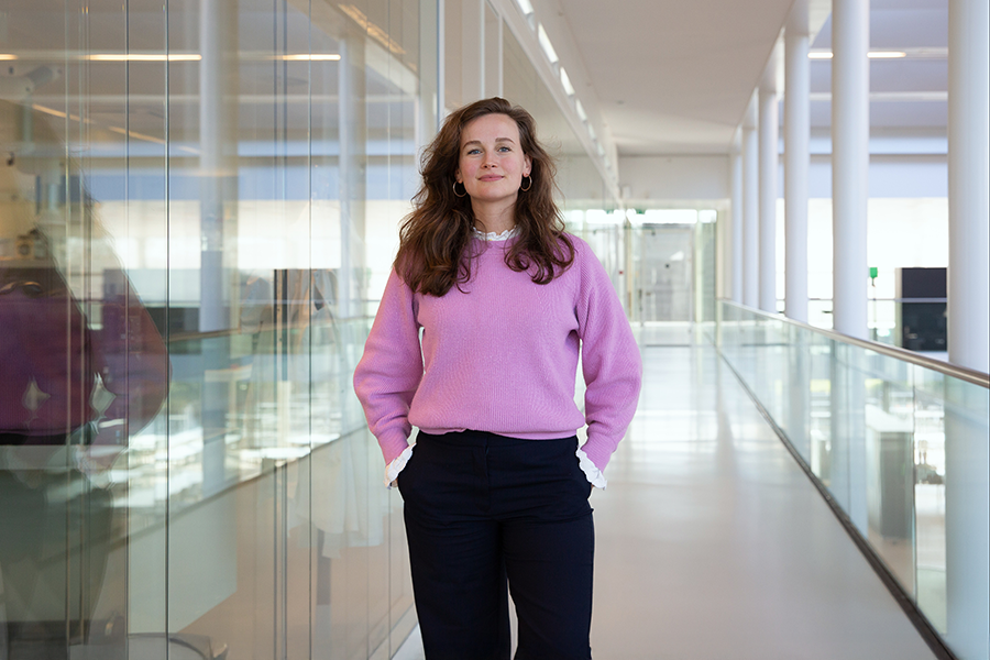 Vrouw met bruin haar en roze trui in lange gang