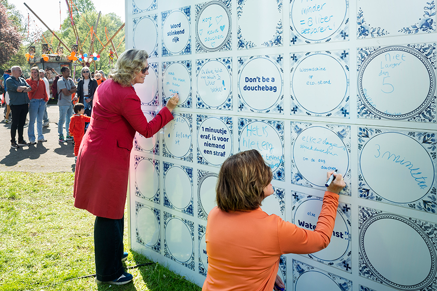 Twee dames schrijven een waterwijsheid op de tegeltjeswand
