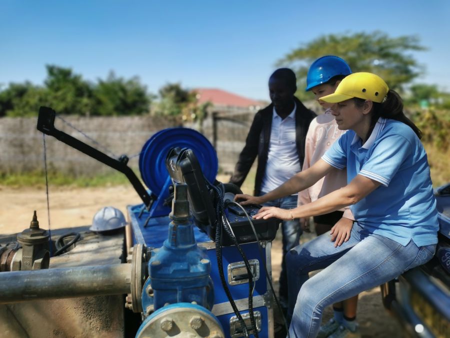 Drie mensen op een rij werken achter een machine in de natuur