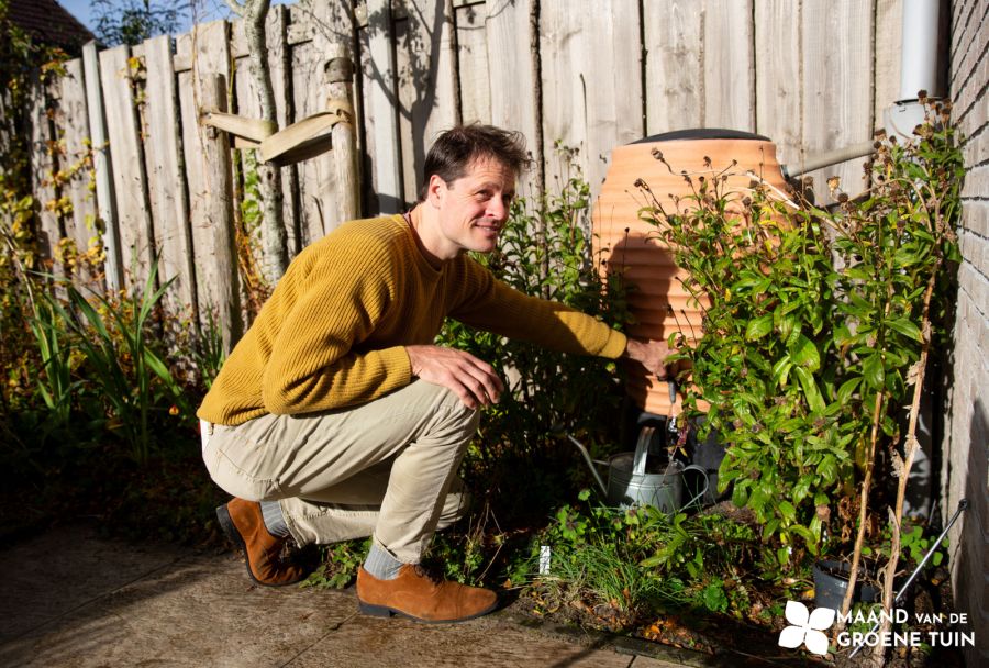 Meneer bij de regenton doet water in een gieter