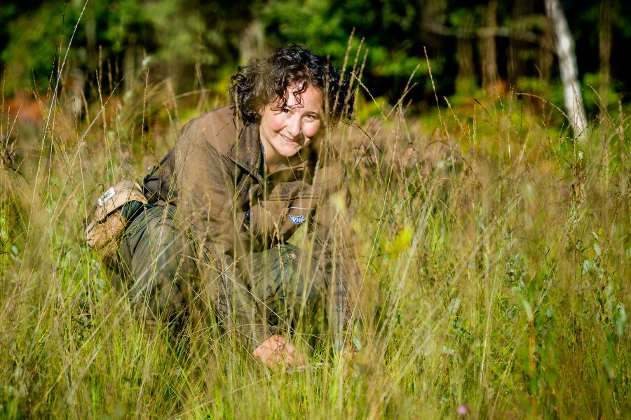 Dame zit gehurkt in het lage gras en glimlacht