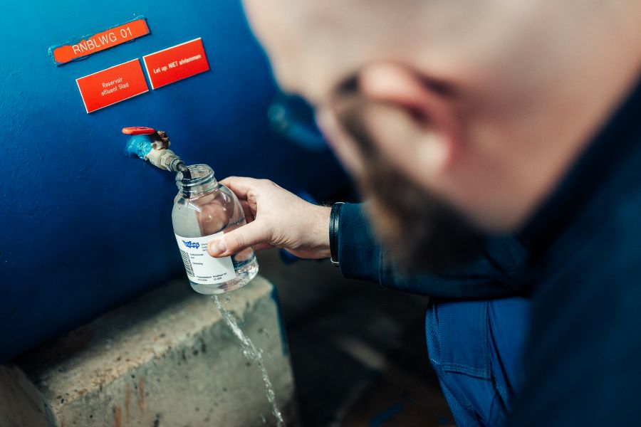 Een man die een flesje vult met water