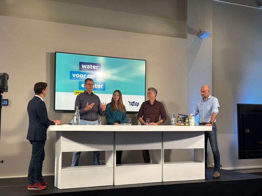 Drie mannen en één vrouw staan om een tafel tijdens het webinar voedingsmiddelenindustrie