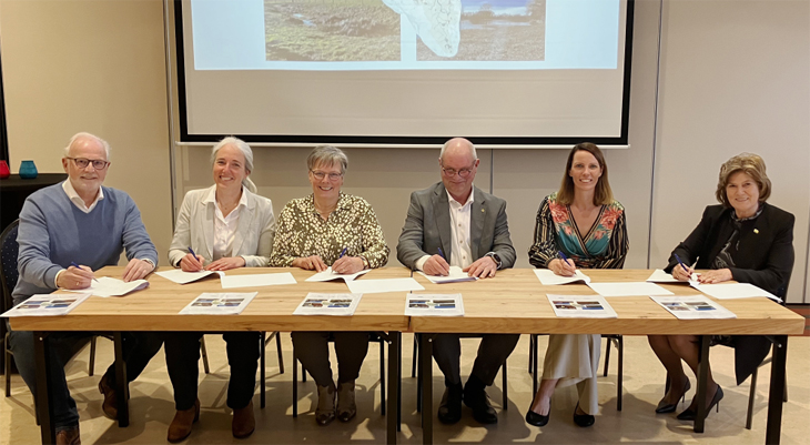 Mensen aan een tafel die een intentieovereenkomst ondertekenen