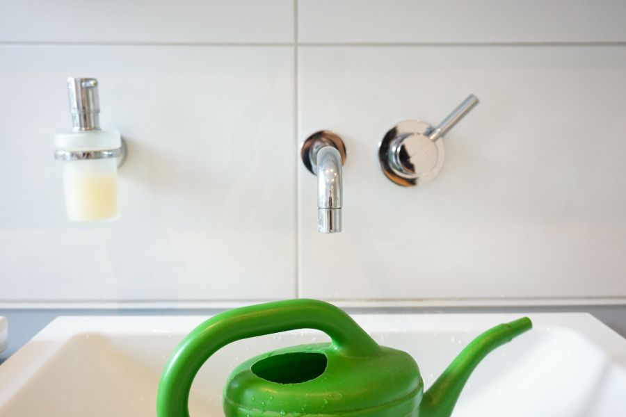 Groene gieter onder badkamerkraan.